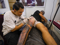 An artist (L) inks a tattoo on the body of an enthusiast (R) during the Himalayan Tattoo Convention in Lalitpur, Nepal, on August 14, 2024....