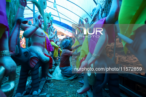 An artist puts a dress and jewelry on the idol of the Hindu lord Bishwokarma, the main craftsman and architect of the gods, at a workshop in...