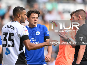 Referee Matthew Donohue has words with Curtis Nelson of Derby County and Perry Ng of Cardiff City during the Sky Bet Championship match betw...