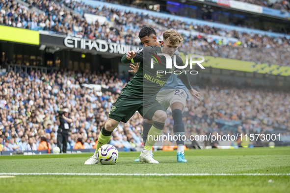 Keane Lewis-Potter #23 of Brentford F.C. is tackled by Savinho #26 of Manchester City F.C. during the Premier League match between Mancheste...