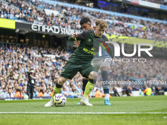 Keane Lewis-Potter #23 of Brentford F.C. is tackled by Savinho #26 of Manchester City F.C. during the Premier League match between Mancheste...