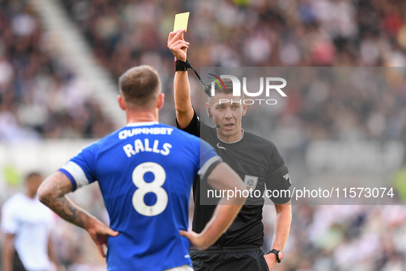 Referee Matthew Donohue shows a yellow card to Joe Ralls of Cardiff City during the Sky Bet Championship match between Derby County and Card...