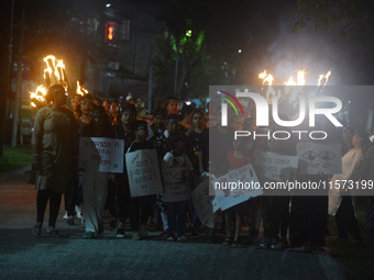 Children hold placards as women and citizens hold burning lanterns as they take part in a protest march to condemn the rape and murder of a...