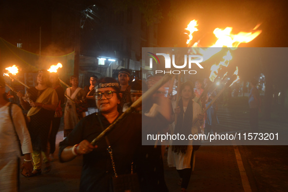 Women and citizens hold burning lanterns as they take part in a protest march to condemn the rape and murder of a young medic in Siliguri, I...