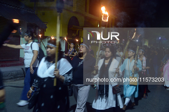 Women and citizens hold burning lanterns as they take part in a protest march to condemn the rape and murder of a young medic in Siliguri, I...