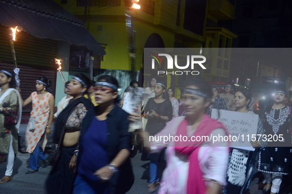 Women and citizens hold burning lanterns as they take part in a protest march to condemn the rape and murder of a young medic in Siliguri, I...