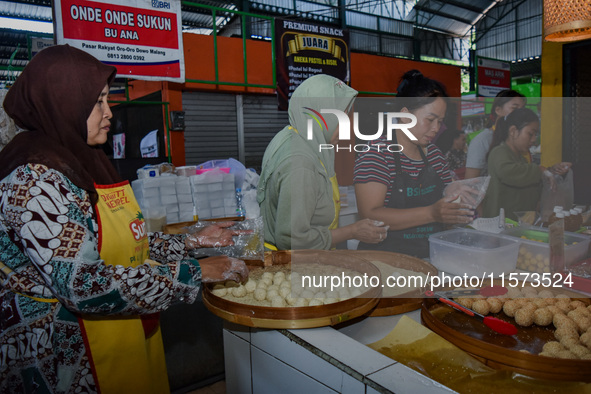 Young people sell Indonesian traditional pancake products (Klepon) at Oro Oro Dowo traditional market in Malang, East Java, Indonesia, on Se...