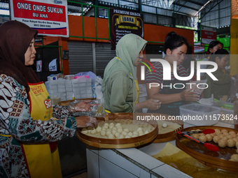 Young people sell Indonesian traditional pancake products (Klepon) at Oro Oro Dowo traditional market in Malang, East Java, Indonesia, on Se...