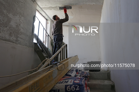 A construction worker restores a multi-storey residential building damaged by Russian shelling in Kharkiv, Ukraine, on September 12, 2024. N...