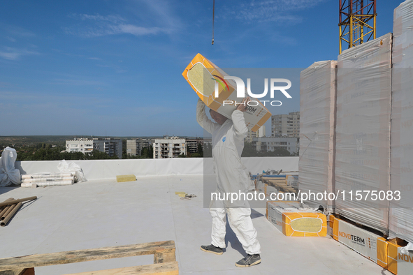 A construction worker restores a multi-storey residential building damaged by Russian shelling in Kharkiv, Ukraine, on September 12, 2024. N...