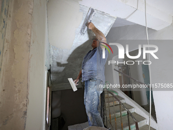 A construction worker restores a multi-storey residential building damaged by Russian shelling in Kharkiv, Ukraine, on September 12, 2024. N...