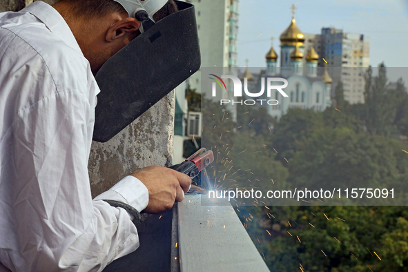 A construction worker restores a multi-storey residential building damaged by Russian shelling in Kharkiv, Ukraine, on September 12, 2024. N...