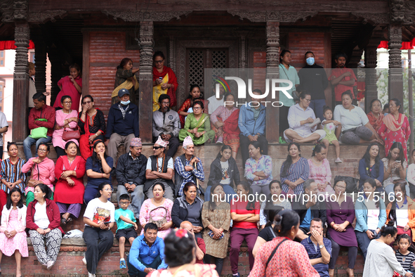 Nepali revelers sit on the stairs of a temple to watch the procession of erecting a sacred pole locally called ''Ya: Shi,'' marking the form...