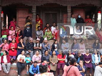 Nepali revelers sit on the stairs of a temple to watch the procession of erecting a sacred pole locally called ''Ya: Shi,'' marking the form...