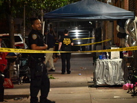 Police stand guard at the scene. Party balloons are visible at the crime scene. One man is dead and another man is injured but expected to s...