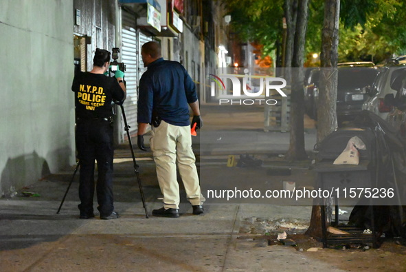 Investigators from the NYPD Crime Scene Unit investigate and place evidence markers and take photographs of the scene. One man is dead and a...