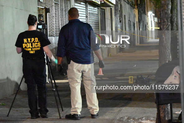 Investigators from the NYPD Crime Scene Unit investigate and place evidence markers and take photographs of the scene. One man is dead and a...