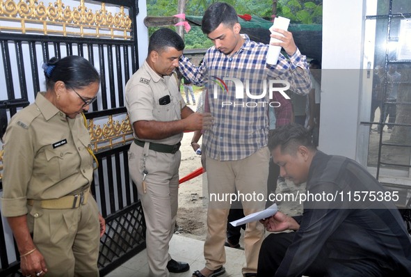 A police officer checks aspirants as they enter an examination hall to appear in the Assam Direct Recruitment Exam 2024 (ADRE) for filling u...