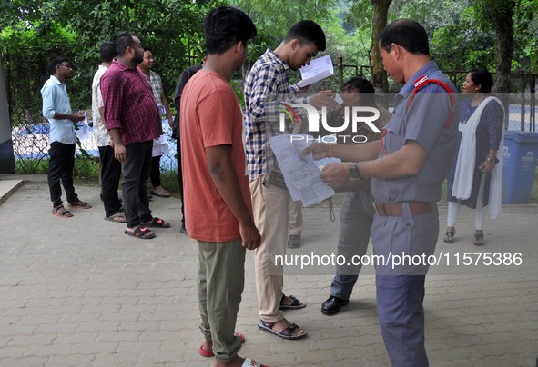 A police officer checks aspirants as they enter an examination hall to appear in the Assam Direct Recruitment Exam 2024 (ADRE) for filling u...