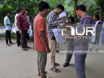 A police officer checks aspirants as they enter an examination hall to appear in the Assam Direct Recruitment Exam 2024 (ADRE) for filling u...