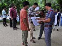 A police officer checks aspirants as they enter an examination hall to appear in the Assam Direct Recruitment Exam 2024 (ADRE) for filling u...