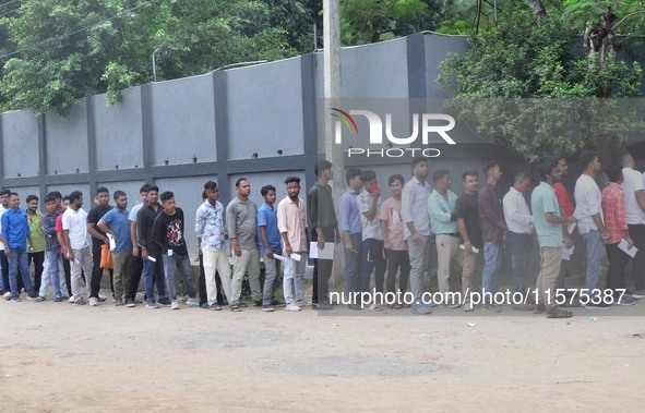 Candidates stand in a queue before appearing in a written examination for vacant Group III posts in the Assam government in Guwahati, India,...