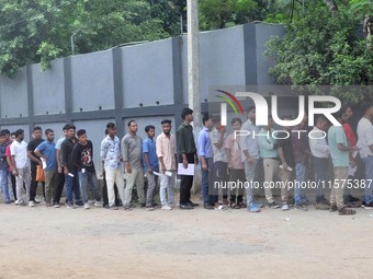 Candidates stand in a queue before appearing in a written examination for vacant Group III posts in the Assam government in Guwahati, India,...