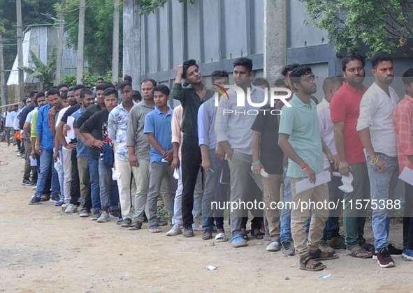 Candidates stand in a queue before appearing in a written examination for vacant Group III posts in the Assam government in Guwahati, India,...