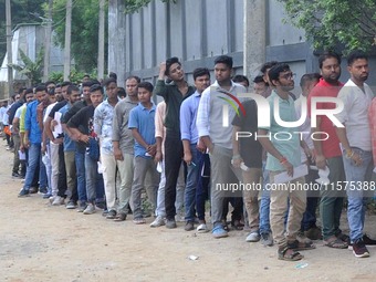 Candidates stand in a queue before appearing in a written examination for vacant Group III posts in the Assam government in Guwahati, India,...