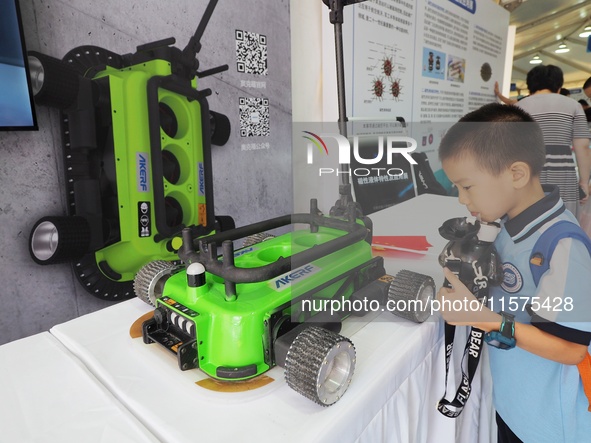 A child visits a ''negative pressure adsorption wall climbing robot'' during the 14th Beijing Science Carnival in Beijing, China, on Septemb...