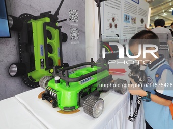 A child visits a ''negative pressure adsorption wall climbing robot'' during the 14th Beijing Science Carnival in Beijing, China, on Septemb...