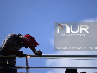 A worker welds an aluminum bar in Kirtipur, Kathmandu, Nepal, on September 15, 2024. He earns a monthly income of NRs. 15,000 (US$ 150) (