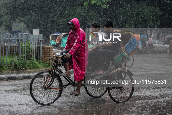 A rickshaw puller wears a raincoat as rain continues in Dhaka, Bangladesh, on September 15, 2024. 