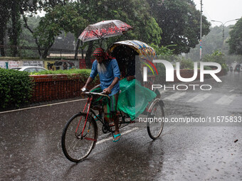 A passenger holds an umbrella to protect himself and the rickshaw puller as rain continues in Dhaka, Bangladesh, on September 15, 2024. (