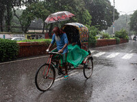 A passenger holds an umbrella to protect himself and the rickshaw puller as rain continues in Dhaka, Bangladesh, on September 15, 2024. (