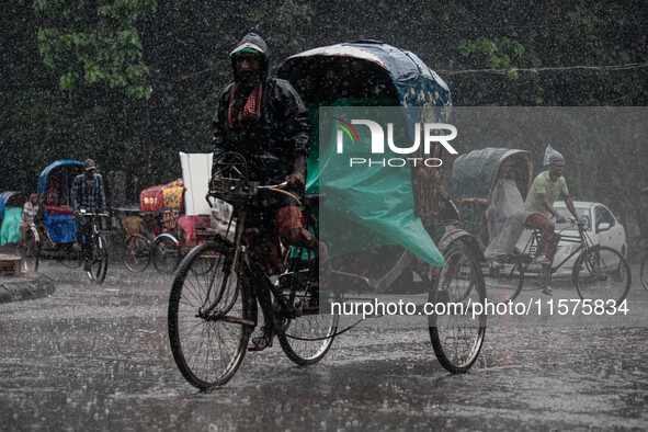 A rickshaw puller wears a raincoat as rain continues in Dhaka, Bangladesh, on September 15, 2024. 