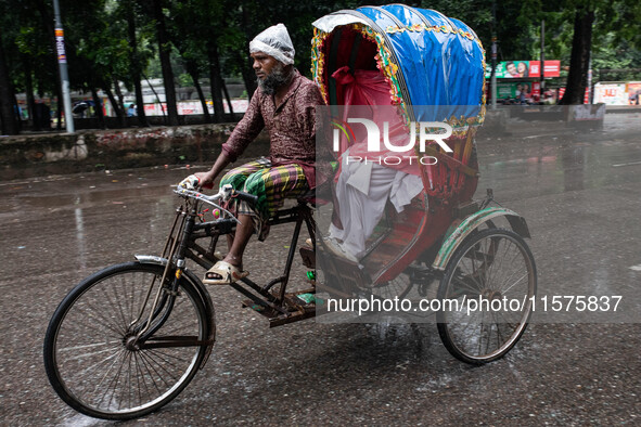 An elderly man without an arm drives an auto-rickshaw in the rain in Dhaka, Bangladesh, on September 15, 2024. 