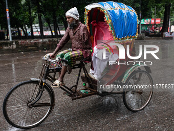 An elderly man without an arm drives an auto-rickshaw in the rain in Dhaka, Bangladesh, on September 15, 2024. (