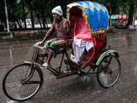 An elderly man without an arm drives an auto-rickshaw in the rain in Dhaka, Bangladesh, on September 15, 2024. (