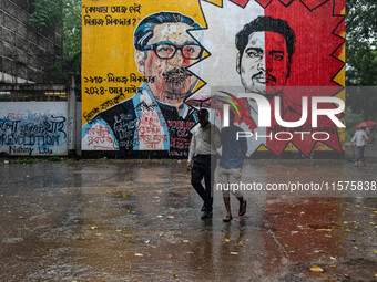 People walk in the rain in front of the wall, where Siraj Sikder's graffiti is next to Sheikh Mujibur Rahman's graffiti, calling him the kil...