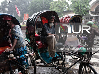 Rickshaw pullers take shelter on their rickshaws as rain continues in Dhaka, Bangladesh, on September 15, 2024. (