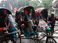 Rickshaw pullers take shelter on their rickshaws as rain continues in Dhaka, Bangladesh, on September 15, 2024. (