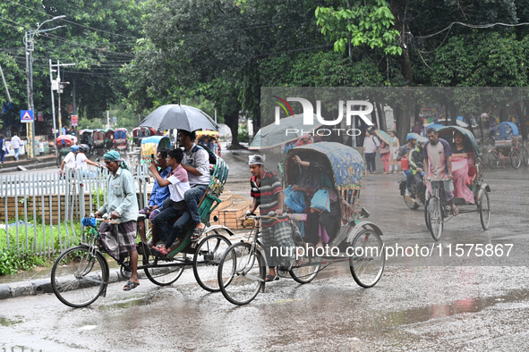 A rickshaw puller with a passenger makes his way along a street during heavy rainfall in Dhaka, Bangladesh, on September 15, 2024. 