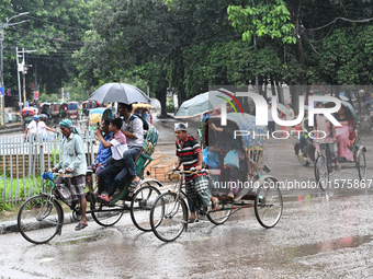 A rickshaw puller with a passenger makes his way along a street during heavy rainfall in Dhaka, Bangladesh, on September 15, 2024. (