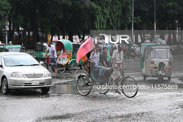 A rickshaw puller with a passenger makes his way along a street during heavy rainfall in Dhaka, Bangladesh, on September 15, 2024. 