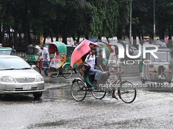 A rickshaw puller with a passenger makes his way along a street during heavy rainfall in Dhaka, Bangladesh, on September 15, 2024. (