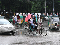 A rickshaw puller with a passenger makes his way along a street during heavy rainfall in Dhaka, Bangladesh, on September 15, 2024. (