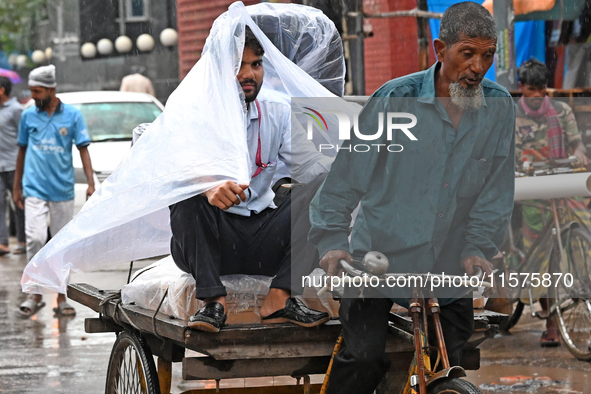 A rickshaw puller with a passenger makes his way along a street during heavy rainfall in Dhaka, Bangladesh, on September 15, 2024. 