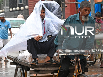 A rickshaw puller with a passenger makes his way along a street during heavy rainfall in Dhaka, Bangladesh, on September 15, 2024. (