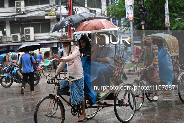 A rickshaw puller with a passenger makes his way along a street during heavy rainfall in Dhaka, Bangladesh, on September 15, 2024. 